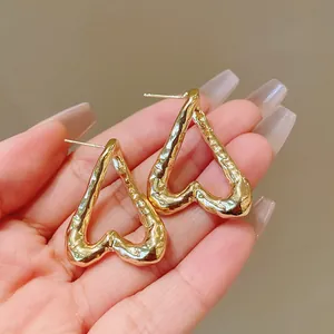 Primer plano de pendientes de metal dorado con textura en forma de corazón y plata.
