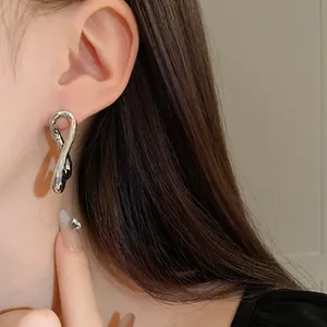 Primer plano de pendientes metálicos plateados con diseño trenzado y textura única