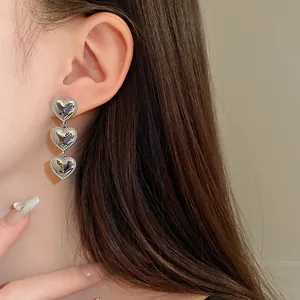 Vista detallada de cerca de los elegantes pendientes colgantes de triple corazón plateados