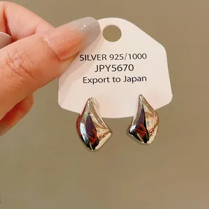 Vista detallada de pendientes de plata irregulares con acabado de espejo brillante