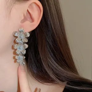 Detalle de los pendientes de flores de metal plateado usados por la modelo