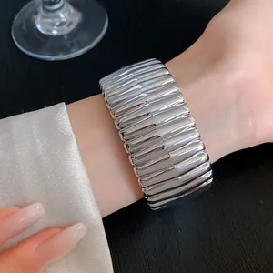 Close-up view of silver geometric ribbed acrylic bangle worn on wrist for detail