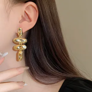 Primer plano detallado que muestra el acabado dorado metálico de los pendientes de frijol abstractos
