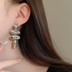 Primer plano de los pendientes largos de metal plateado martillado usados por una modelo