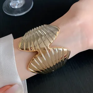 Detailed close-up of a stylish gold-toned textured geometric open cuff bangle on a wrist