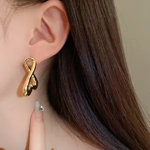Primer plano de pendientes de metal dorado retorcido en la oreja de la modelo, elegante.