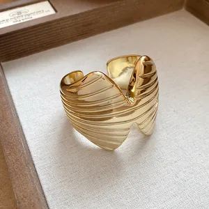 Detail shot of a wide gold-colored textured cuff bracelet with geometric patterns.