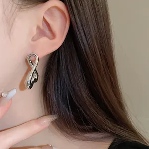 Vista detallada de pendientes de metal líquido plateado en una modelo asiática
