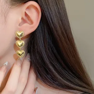 Elegantes pendientes colgantes de tres corazones dorados con estética romántica en una modelo