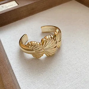 Close-up of gold-plated cuff bracelet featuring intricate shell-like textured design details.