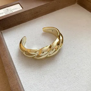 Close-up showing the elegant twisted texture of the gold open cuff bracelet.