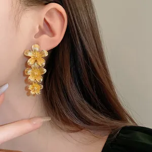 Primer plano detallado de elegantes pendientes colgantes con tres flores doradas