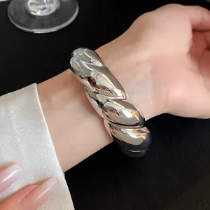 Close-up of a silver-toned chunky twisted cuff bracelet worn on a wrist