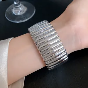 Detailed view of a silver textured chunky open bangle worn on a wrist showing high luster