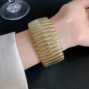 Close-up detail of a chunky gold-toned ribbed cuff bracelet for a luxury look