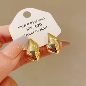 Primer plano de elegantes pendientes dorados en forma de gota con acabado metálico