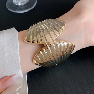 Close-up of gold geometric shell cuff bracelet with elegant ribbed texture on wrist