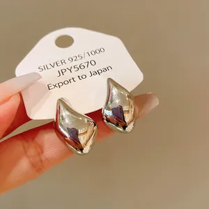Primer plano detallado de pendientes de botón de metal plateado en forma de gota