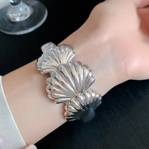 Close-up detail of a silver acrylic seashell textured cuff bracelet worn on a woman's wrist