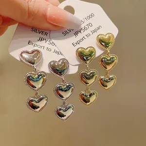 Vista detallada de elegantes pendientes colgantes de triple corazón en oro y plata