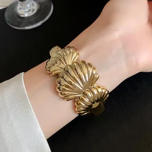 Detailed macro view of a golden acrylic shell pattern open cuff bracelet worn on wrist