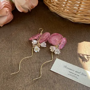 Détail de boucles d'oreilles françaises avec fleurs en résille rose et glands perles