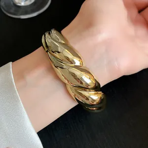 Detailed view of a chunky gold twisted bangle bracelet with glossy metallic finish.