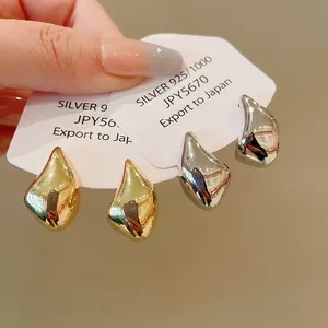 Primer plano detallado de pendientes metálicos de gota en oro y plata