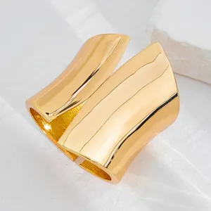 Close-up of polished gold asymmetrical wide metal cuff bracelet with mirror finish