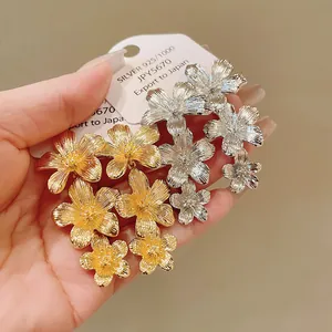 Primer plano detallado de pendientes de flores de oro y plata texturizados.