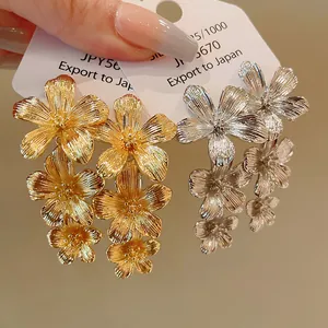 Primer plano detallado de pendientes florales metálicos en tonos dorados y plata