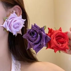 Primo piano di orecchini a forma di rosa in tessuto nei colori lavanda, viola e rosso