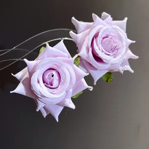 Macro dei dettagli degli orecchini a rosa in tessuto lilla con gocce di rugiada.