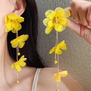 Close-up of yellow chiffon flower tassel earrings showing delicate fabric texture