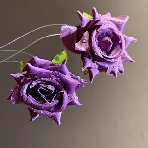 Primo piano di orecchini a fiore in tessuto viola con gocce d'acqua e perni in argento