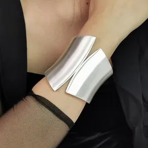 Close-up of wide asymmetrical silver cuff bracelet with brushed metal texture on arm