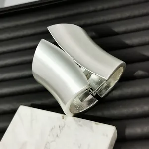 Close-up detail of a wide asymmetrical metal cuff bracelet with brushed silver finish.