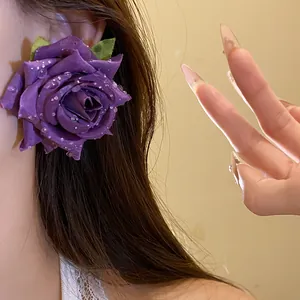 Dettaglio di un elegante orecchino a rosa in tessuto viola con perline effetto rugiada