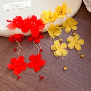 Close-up of red and yellow chiffon flower tassel earrings on a wooden display