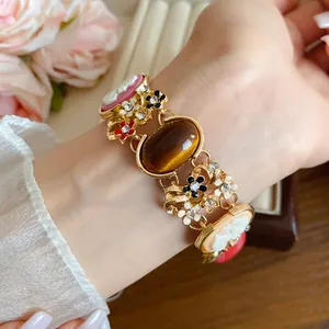 Detail view of a vintage French bracelet with floral and cameo resin charms on a wrist.