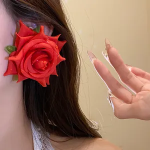 Primo piano di un orecchino a rosa in tessuto rosso con dettagli a goccia di rugiada