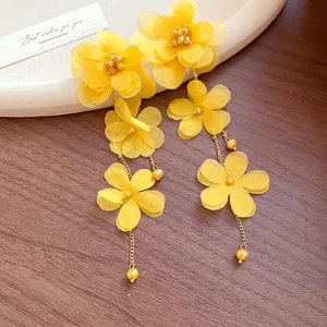 Detailed view of yellow chiffon flower earrings with long golden chain tassels