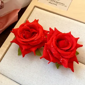 Dettaglio macro di orecchini a rosa in tessuto rosso con realistiche gocce d'acqua