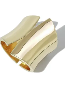 Close-up of minimalist asymmetric gold metallic wide cuff bracelet with polished finish.