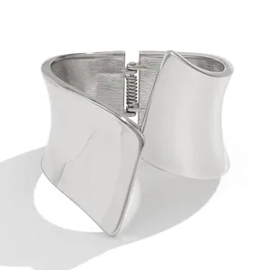 Detailed macro view of a wide asymmetric silver metal bangle with a smooth polished finish