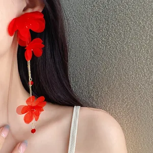 Close-up of elegant red chiffon flower tassel earrings with glass beads on a model