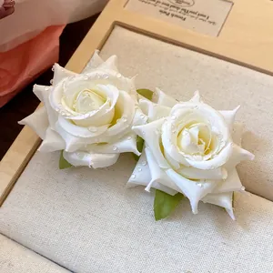 Primo piano di eleganti orecchini a lobo a rosa in tessuto bianco con perline