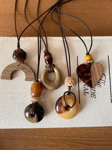 Detail view of four vintage wooden and resin pendant necklaces on natural canvas.