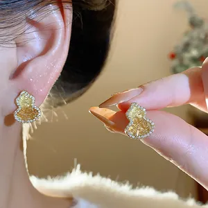 Detail view of gold-plated wulu gourd earrings inlaid with zircons on a model's ear