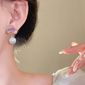 Elegant flower pearl drop earrings on Asian model, luxury fashion accessory.
